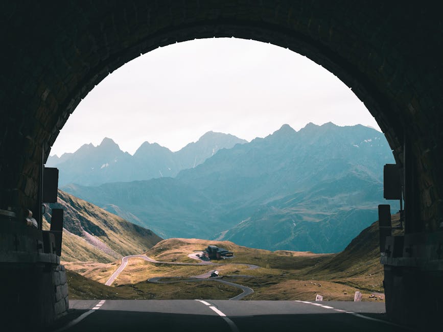 Scenic drive view through a tunnel overlooking mountains and winding road.
